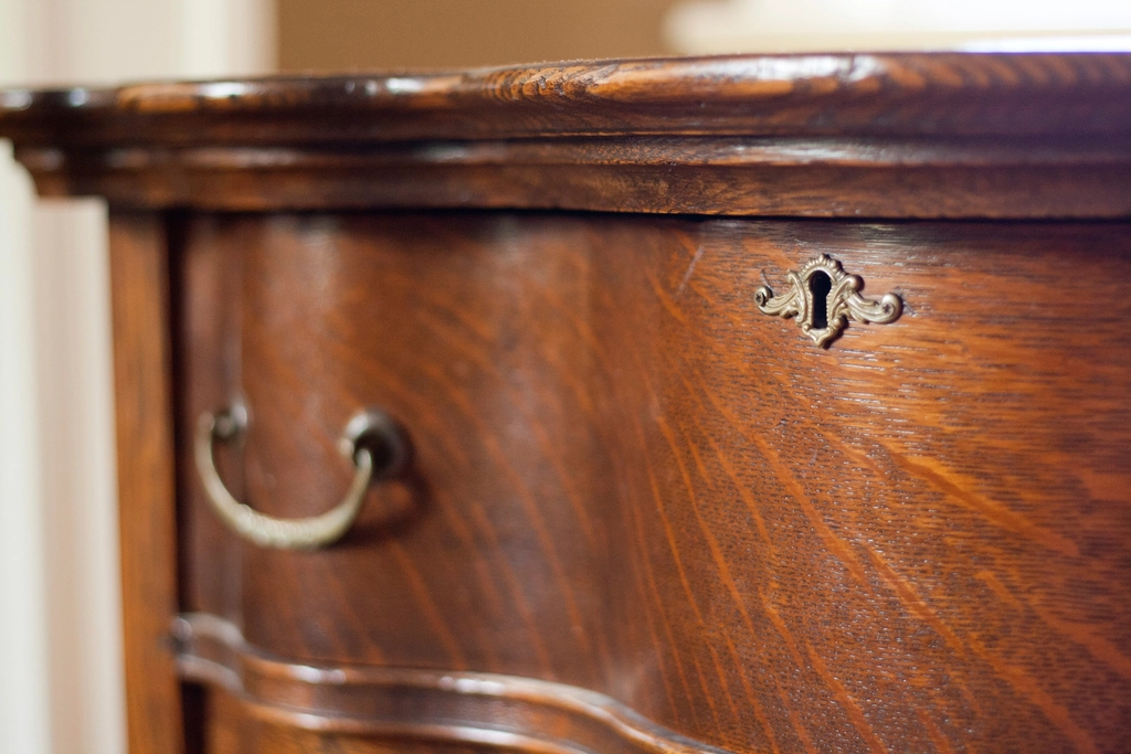 An antique wooden writing desk with a small drawer and an old key.