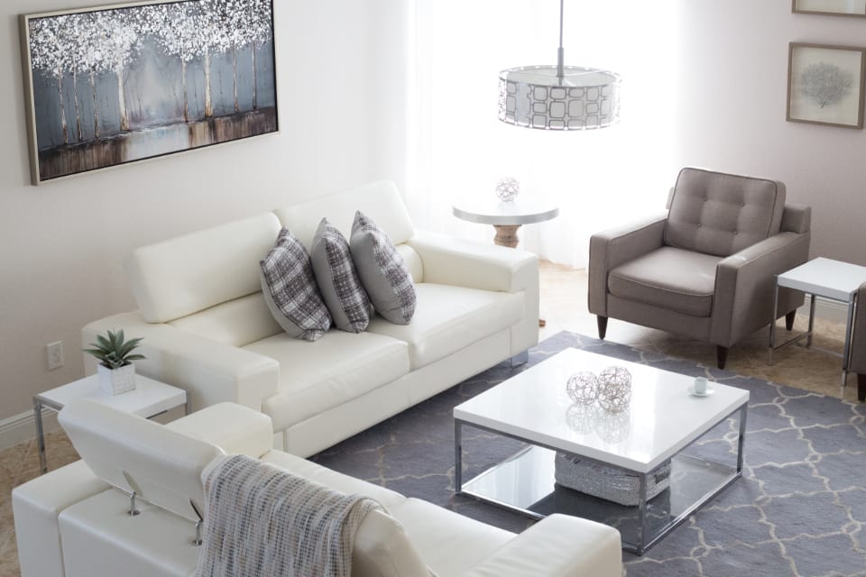 A calm living room with a sofa and armchairs lit by a large window.