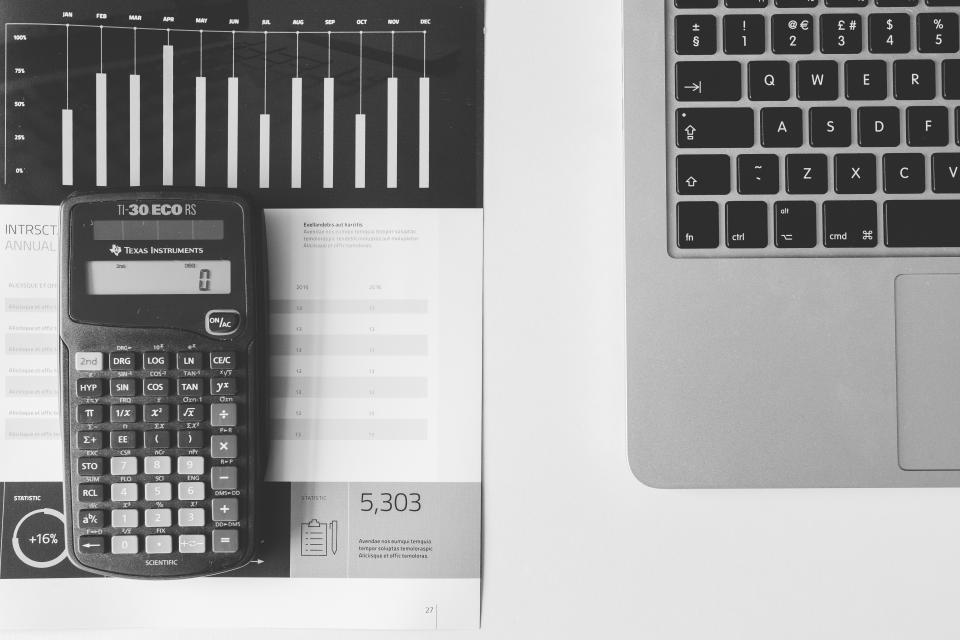 A calculator resting on printed financial paperwork on a desk.